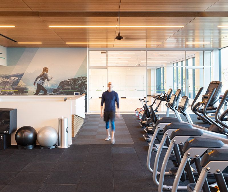 Gym space with two exercise balls and a row of exercise machines including ellipticals and stationary bikes. 
