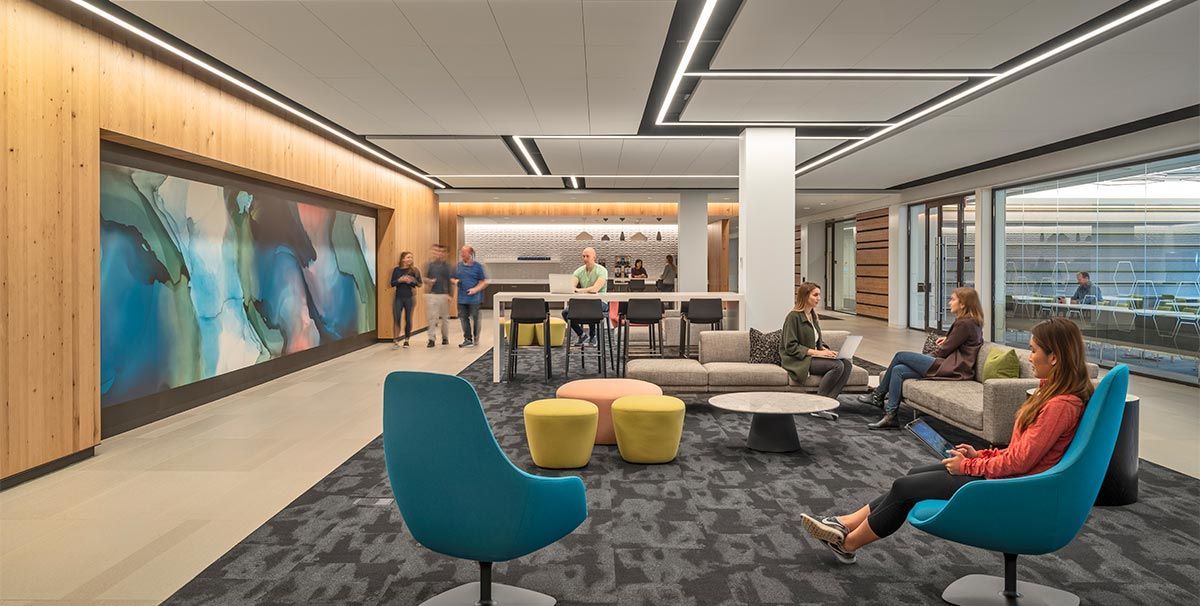 Lounge and collaboration space with casual seating and large modern art panel on the wall. 