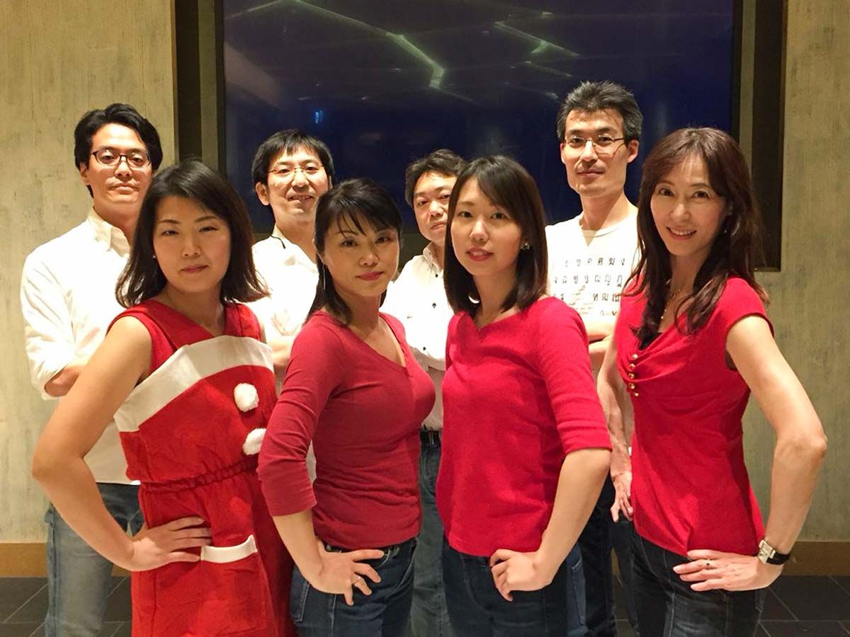 Group of four men in white shirts and four women in red shirts posing in an arranged stance. 