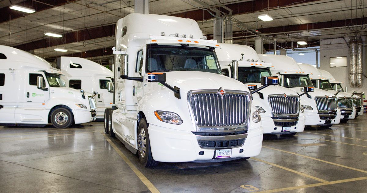 Fleet of trucks parked inside a large garage.